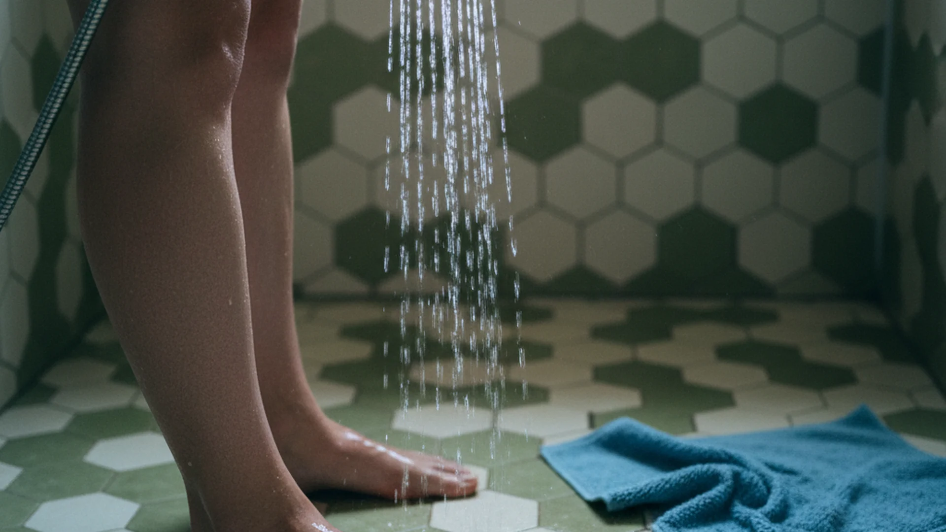 Gros plan d'une femme enceinte passant un jet d'eau froide sur ses jambes dans sa salle de bain