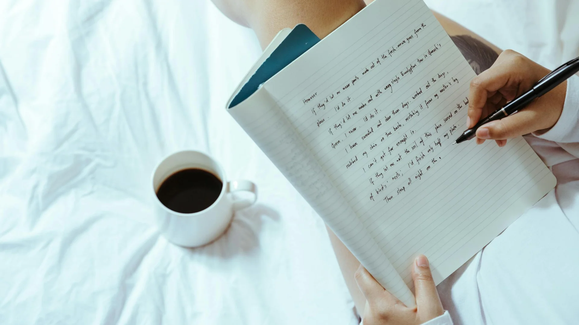 Femme écrivant dans un carnet de suivi sur un lit cosy, avec une tasse de café à côté, pour noter ses cycles après l'arrêt de la pilule
