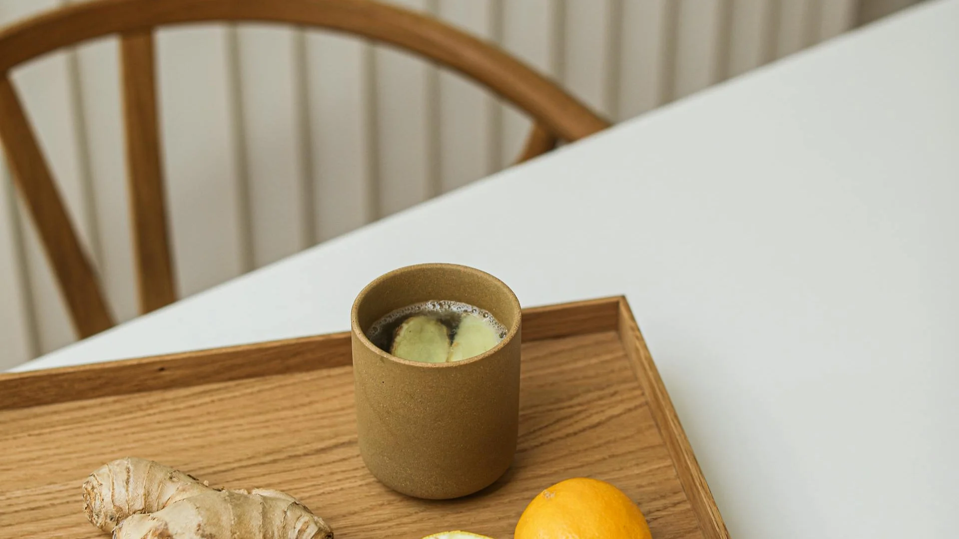 Tasse de tisane au gingembre et au citron posée sur un plateau en bois, lumière douce